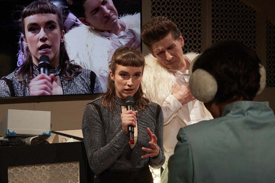 Das Bild zeigt Ruth Bohsung mit Mikro in der Hand, mit Lorenz Hochhuth schaut sie in eine Kamera auf der Bühne