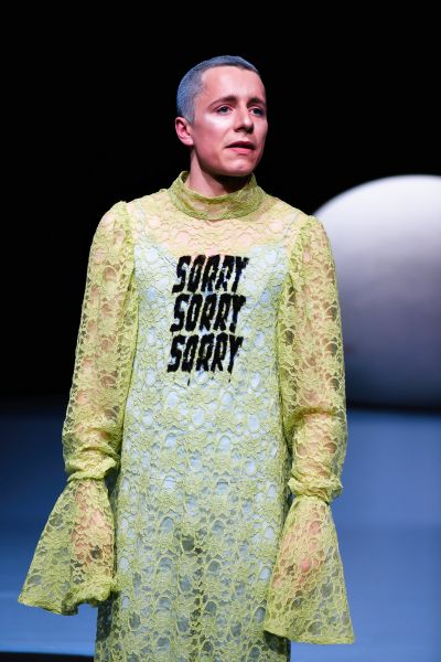 Ein Mann in einem grünen Spitzen-Jumpsuit auf dem dreimal "Sorry" steht