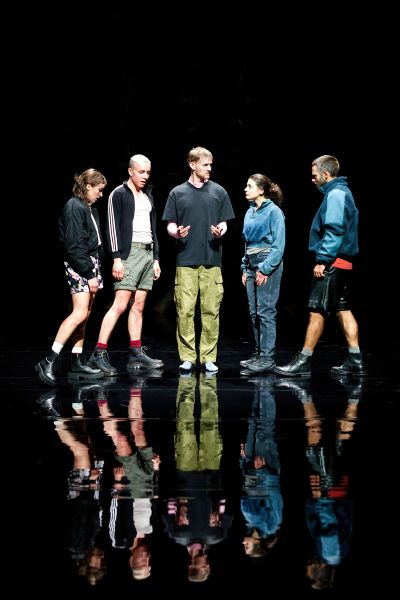 Ein Foto der fünf Darsteller*innen. Man sieht ihre Reflektionen auf dem Boden.