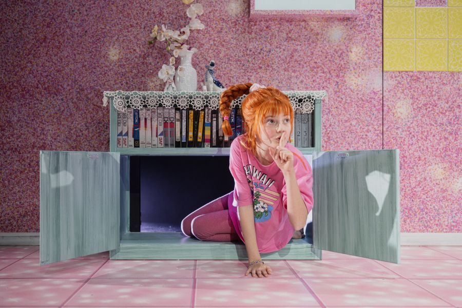 Eine Schauspielerin in pink gekleidet klettert aus einer Luke