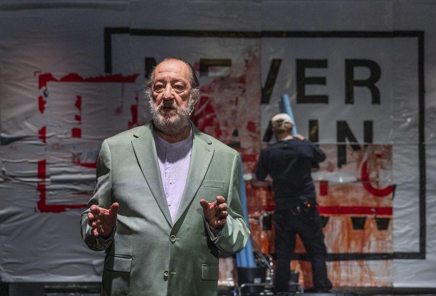 Ein Performer vor einer Wand auf der steht &quot;Never Again. Now.&quot;