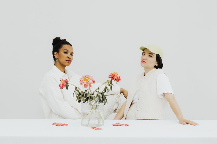 Das Duo Olicía hinter einem Strauß Rosen