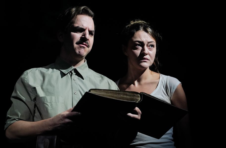 Pascal Fligg betrachtet skeptisch das Fotoalbum in seinen Händen. Lola Dockhorn steht neben ihm und blickt nachdenklich nach vorne.